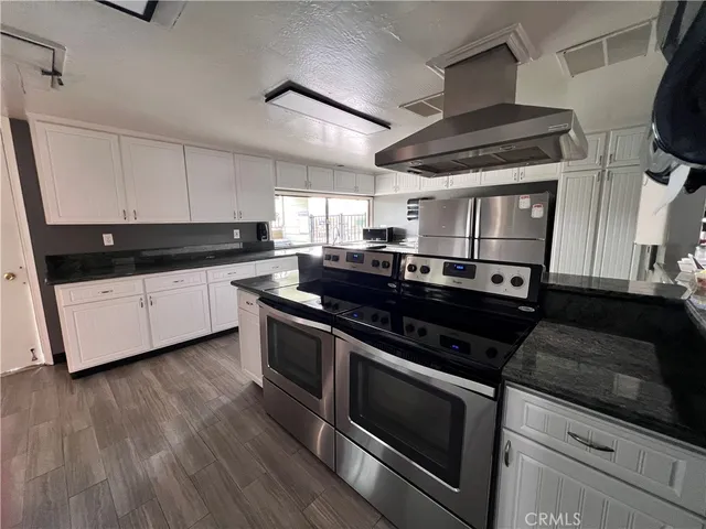 a kitchen with stainless steel appliances granite countertop a stove a sink and white cabinets