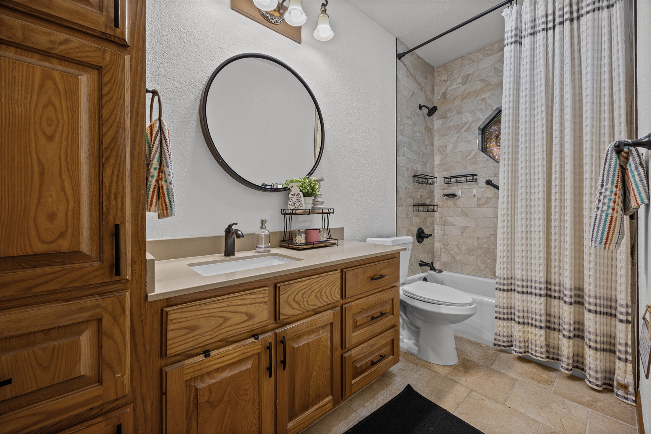 2000 Spinel Road Pflugerville, TX 78660 - Photo 11 of 31 A well-appointed bathroom features a wood vanity, an elegant mirror, and a tiled shower-tub combination.