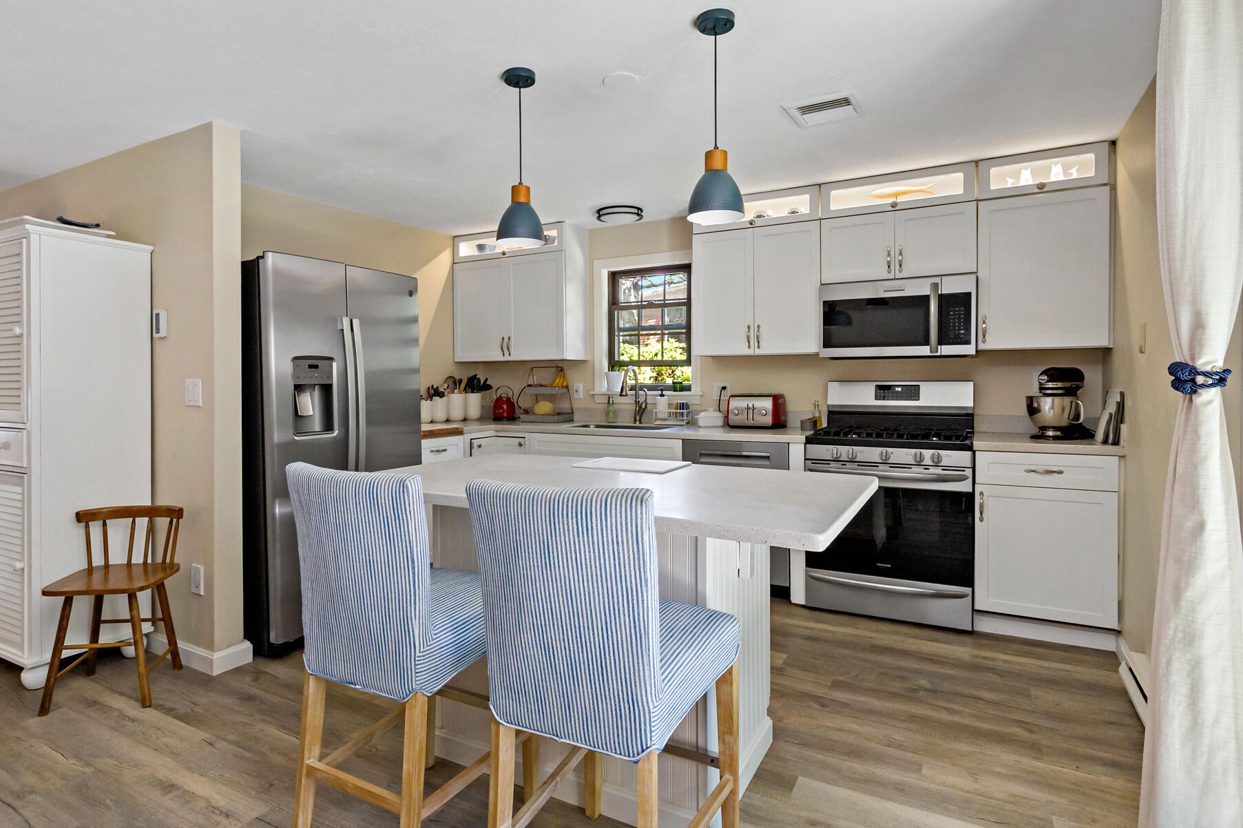 195 Falmouth Road, Unit 16A Mashpee, MA 02649 - Photo 10 of 43 a kitchen with stainless steel appliances granite countertop a stove a sink a microwave a refrigerator a dining table and chairs with wooden floor