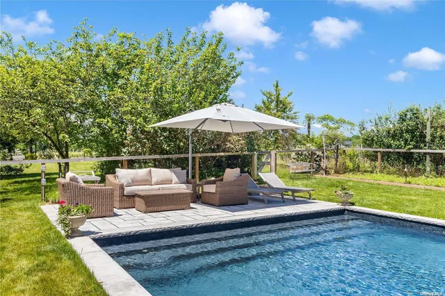 a view of a patio with couches table and chairs under an umbrella