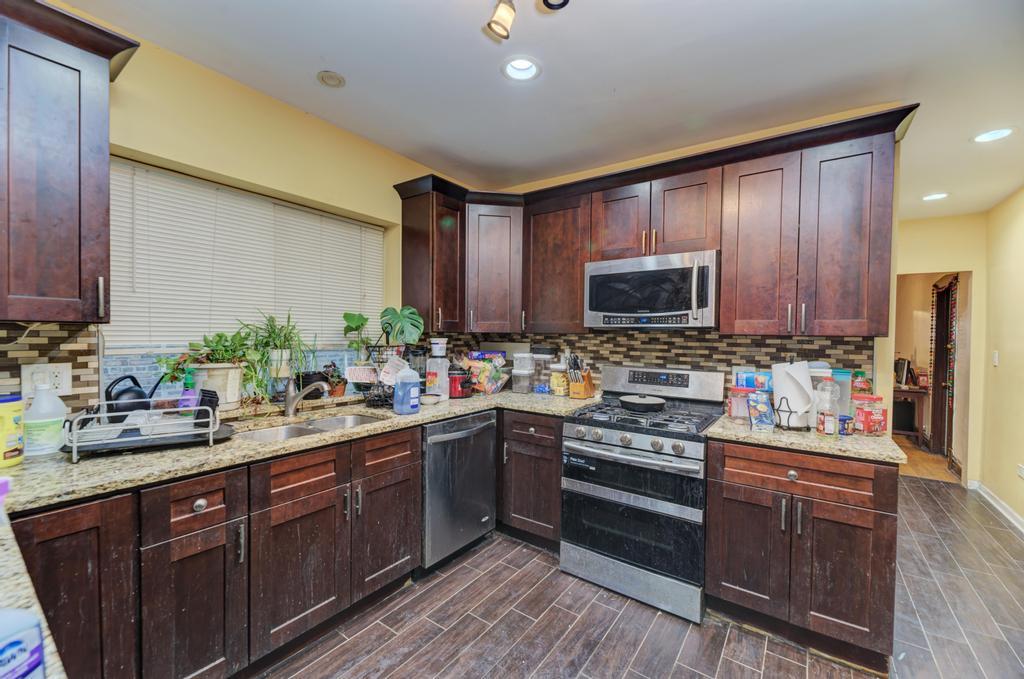 1941 North Harding Avenue Chicago, IL 60647 - Photo 30 of 44 a kitchen with stainless steel appliances a sink dishwasher a stove top oven a refrigerator with wooden cabinets and floor