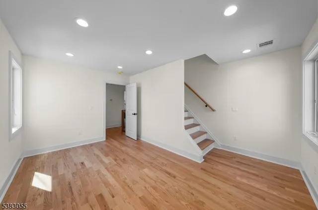 a view of an empty room with wooden floor and stairs