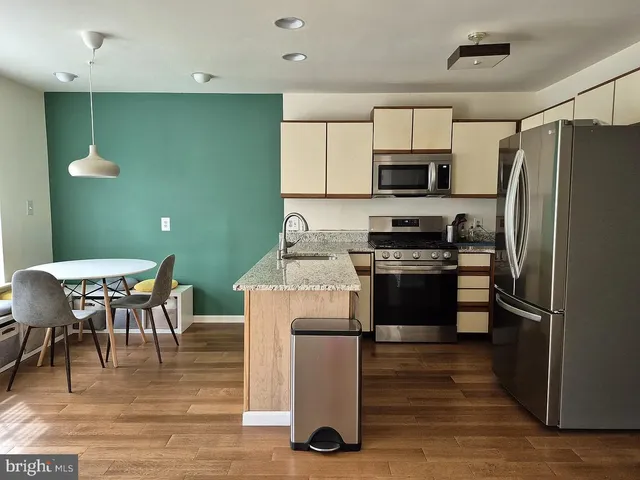 a kitchen with kitchen island a stove a refrigerator and a dining table