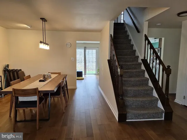 a dining room with wooden floor a chandelier a wooden table and chairs
