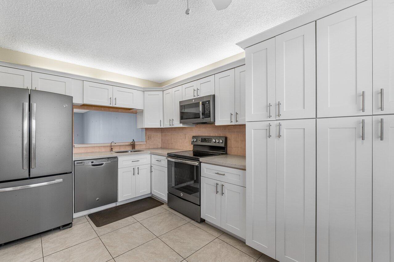 6530 Boca Del Mar Drive, Unit 336 Boca Raton, FL 33433 - Photo 8 of 22 a kitchen with white cabinets stainless steel appliances and sink