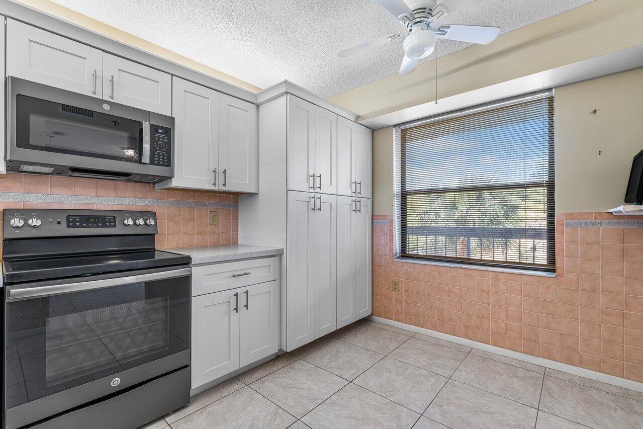 6530 Boca Del Mar Drive, Unit 336 Boca Raton, FL 33433 - Photo 9 of 22 a kitchen with white cabinets stainless steel appliances and a window