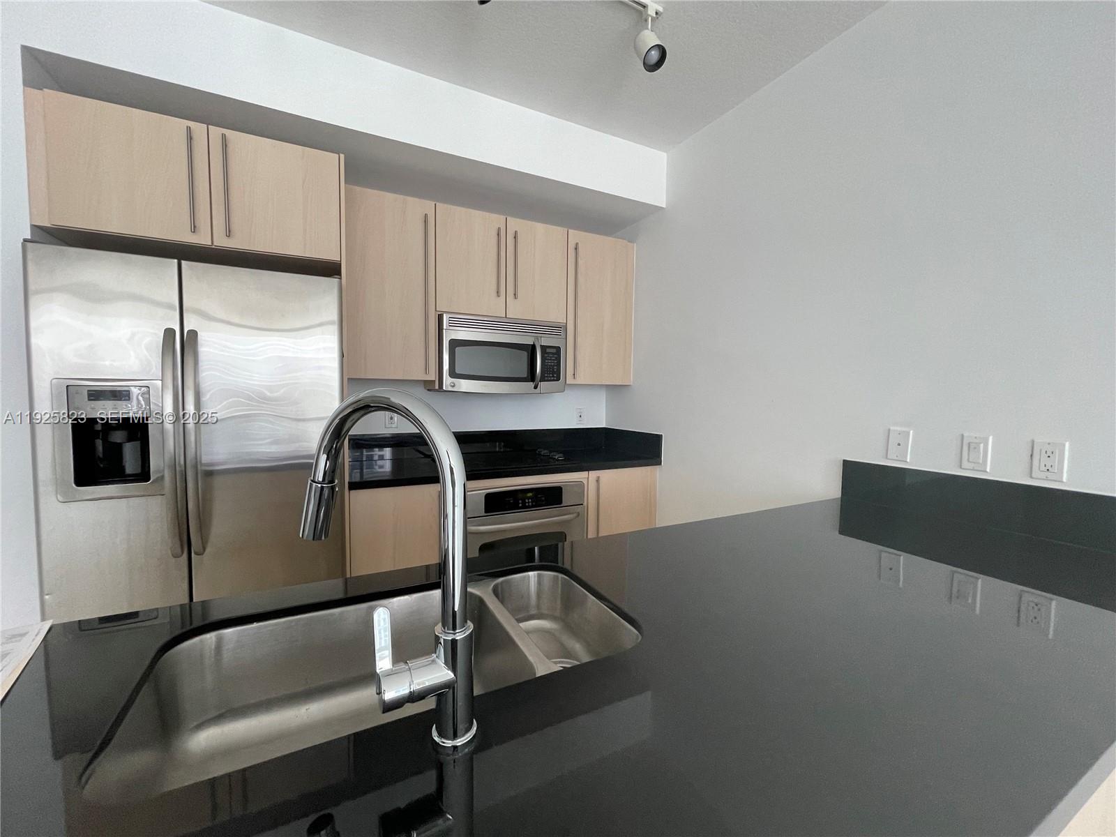1111 Southwest 1st Avenue, Unit 2524N Miami, FL 33130 - Photo 8 of 11 a kitchen with stainless steel appliances a refrigerator a sink a stove white cabinets and chairs