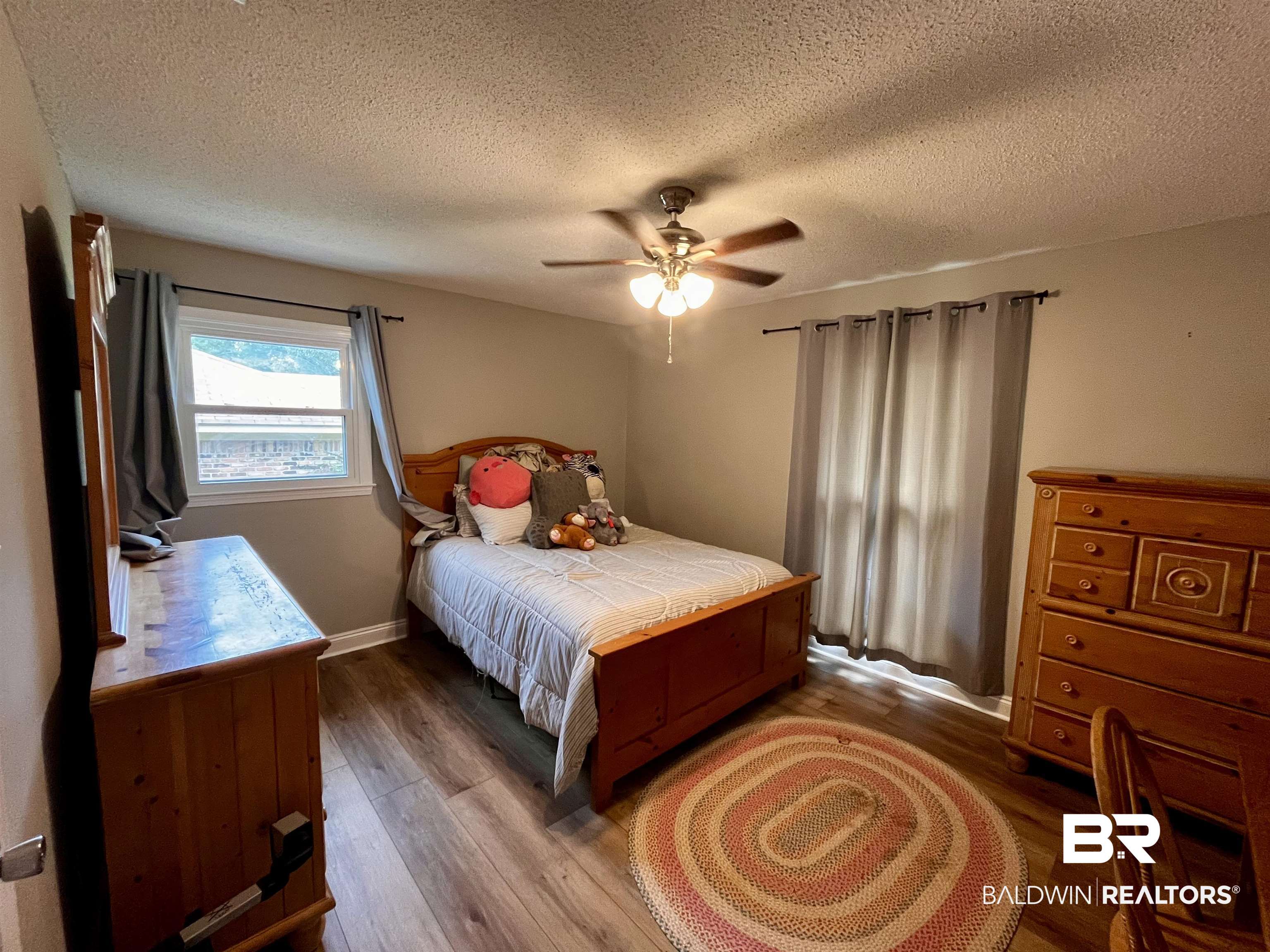 6429 Pinehurst Run Mobile, AL 36608 - Photo 10 of 15 Room featuring wood-finish flooring, two windows with curtain rods, and a ceiling fan with integrated lighting