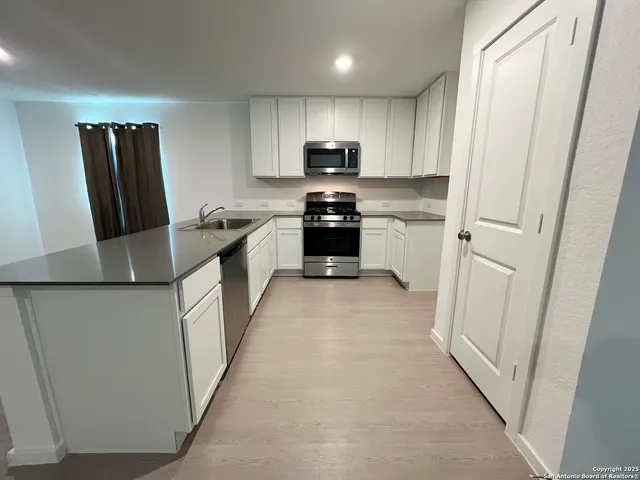 a kitchen with white cabinets and sink