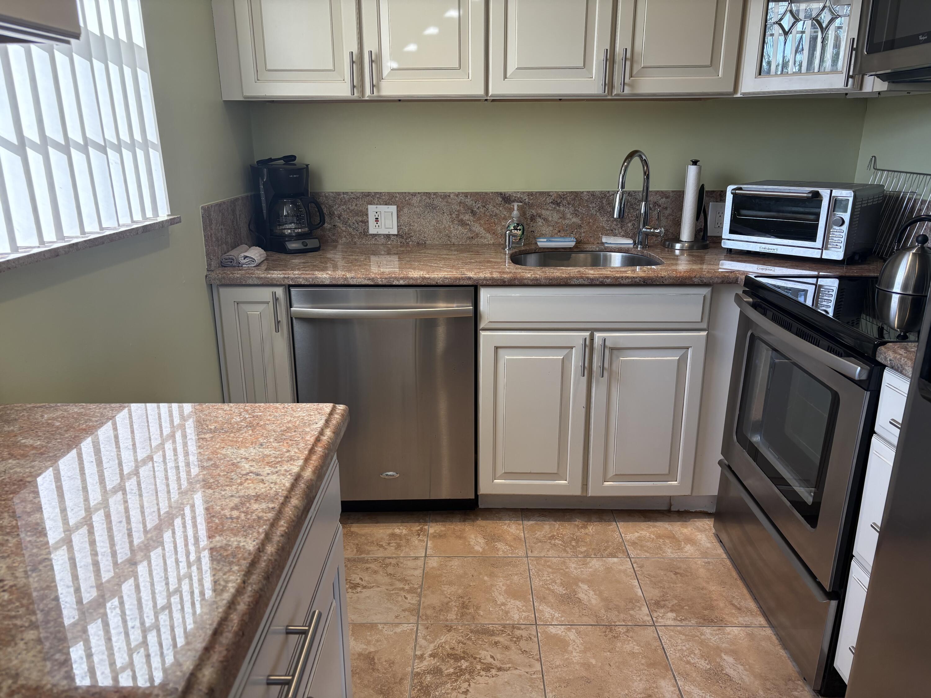 154 Preston F, Unit 154D Boca Raton, FL 33434 - Photo 2 of 17 a kitchen with stainless steel appliances granite countertop a refrigerator sink and cabinets
