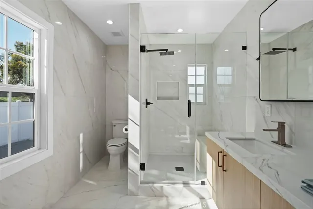 a bathroom with a granite countertop sink a toilet and shower