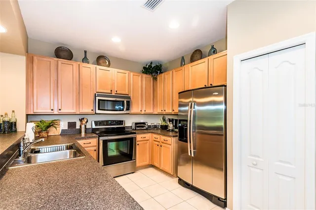 a kitchen with granite countertop a refrigerator a sink a stove top oven a large window and cabinetry