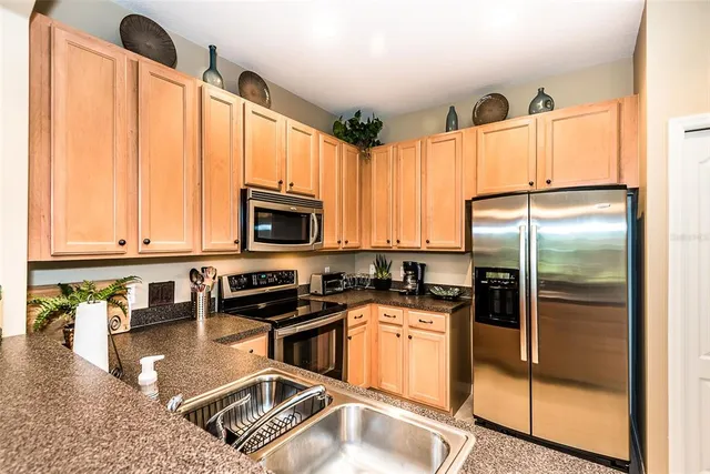 a kitchen with stainless steel appliances granite countertop a refrigerator a sink a stove with cabinets