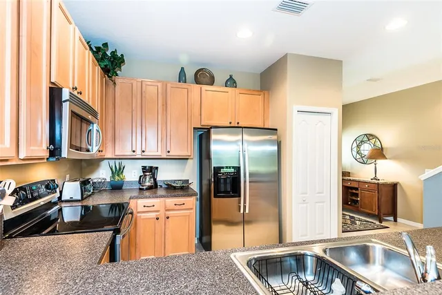 a kitchen with stainless steel appliances granite countertop a refrigerator a sink and a stove