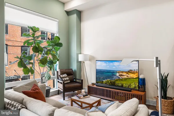 a living room with furniture floor to ceiling window and a flat screen tv