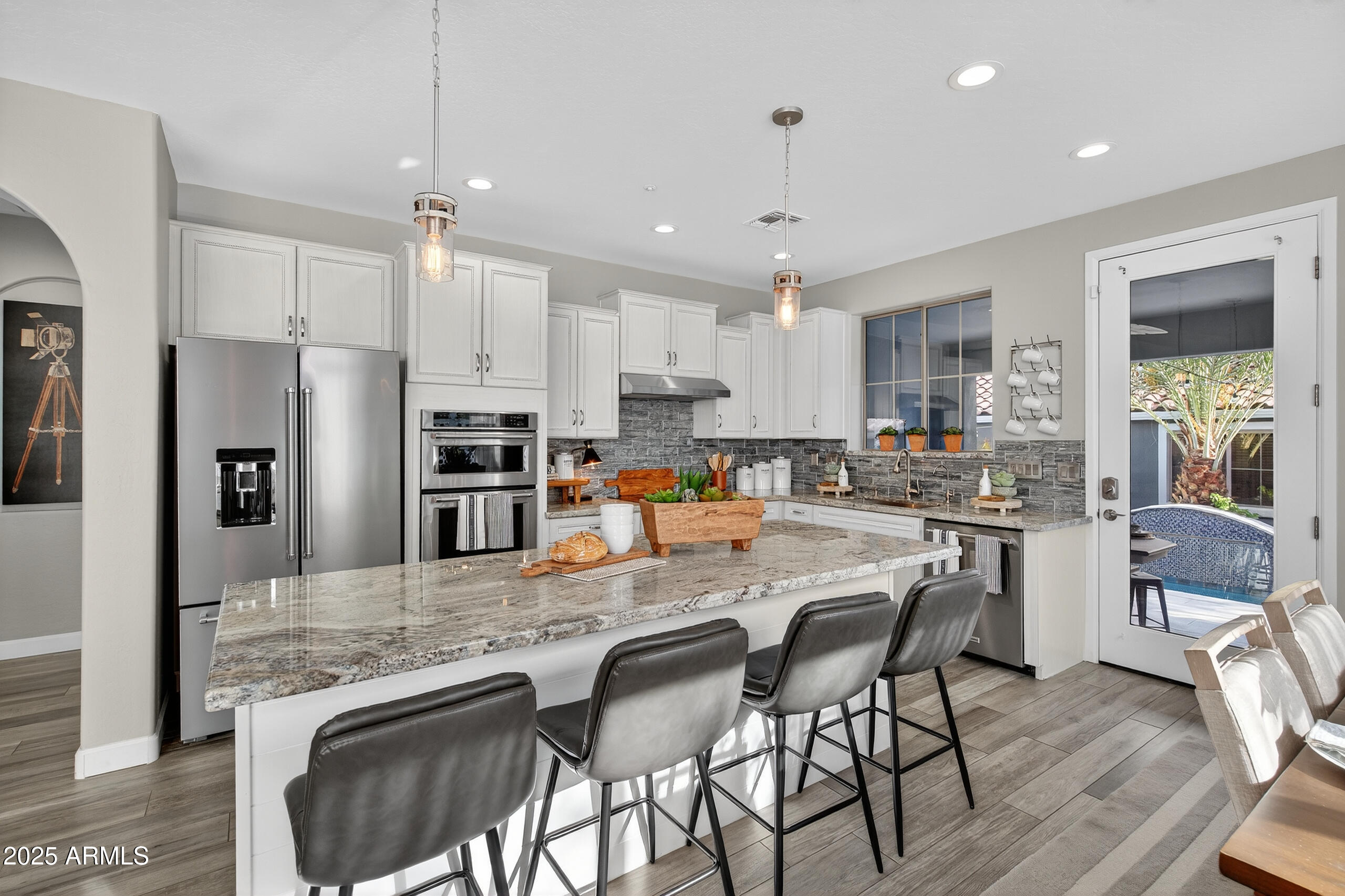 3021 East Agritopia Loop North Gilbert, AZ 85296 - Photo 13 of 68 a kitchen with stainless steel appliances granite countertop a stove top oven a refrigerator a sink and chairs