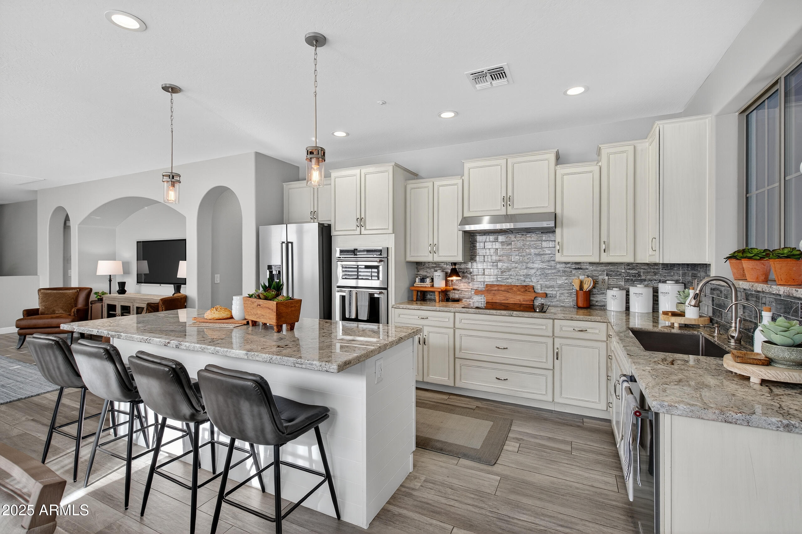 3021 East Agritopia Loop North Gilbert, AZ 85296 - Photo 10 of 68 a kitchen with stainless steel appliances kitchen island granite countertop a stove a sink a refrigerator and white cabinets with wooden floor
