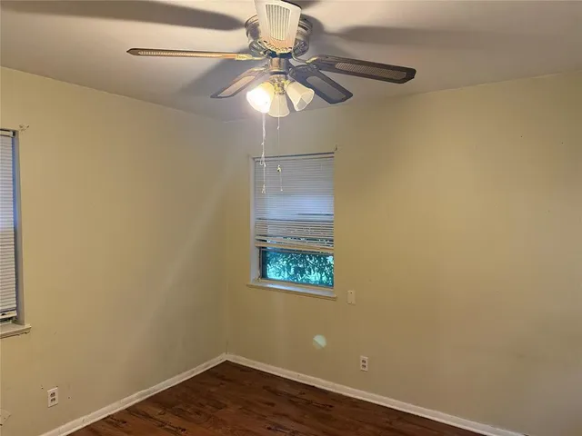 an empty room with wooden floor and fan