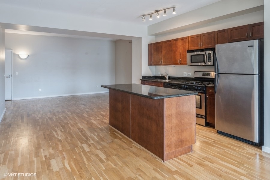 4848 North Sheridan Road, Unit 208 Chicago, IL 60640 - Photo 4 of 15 a kitchen with stainless steel appliances granite countertop a refrigerator a stove and a wooden floors