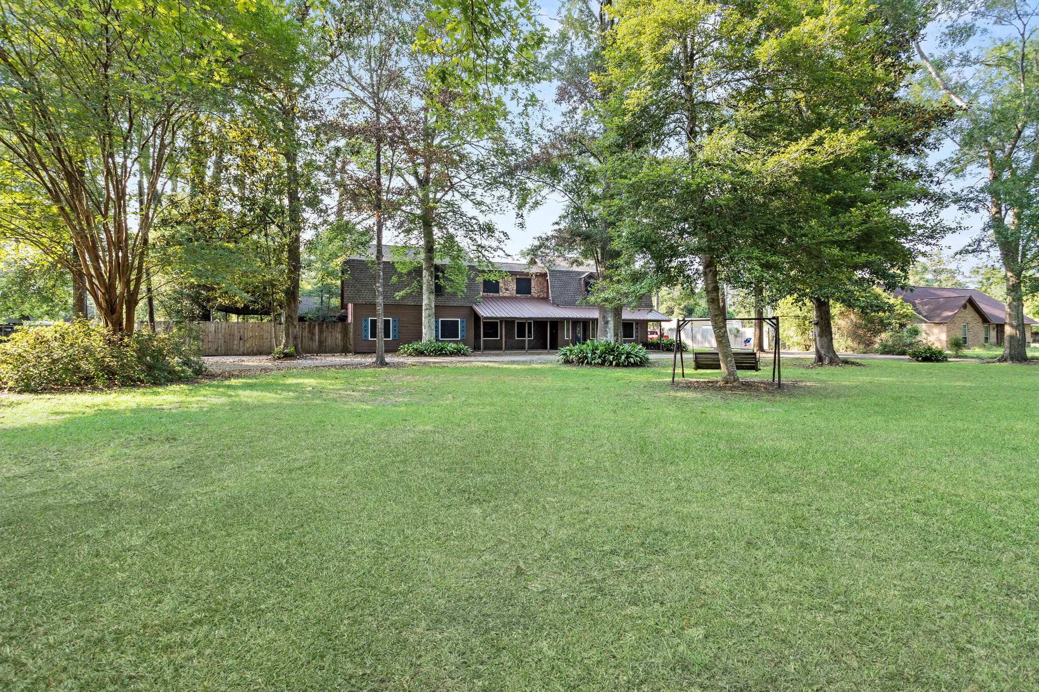 a view of a house with a big yard and large trees