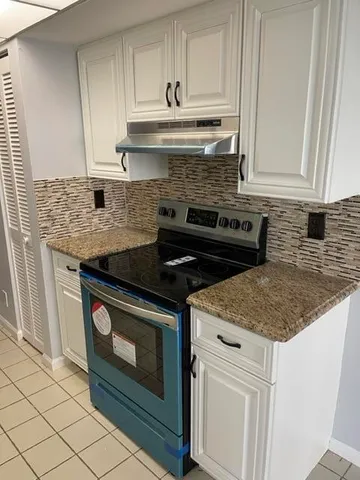 a kitchen with granite countertop white cabinets and stainless steel appliances