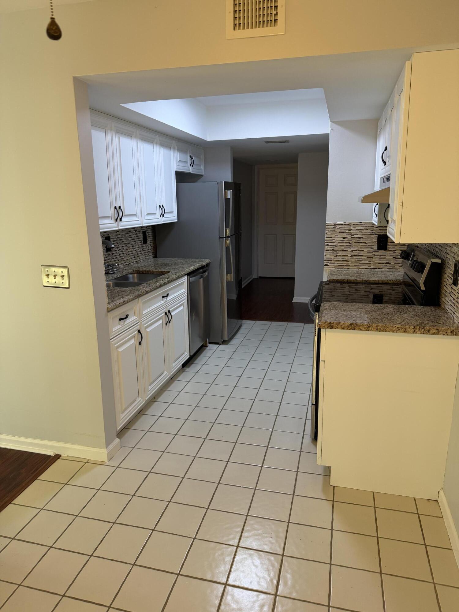 12628 Shoreline Drive, Unit 9C Wellington, FL 33414 - Photo 8 of 32 a kitchen with a sink a stove and cabinets