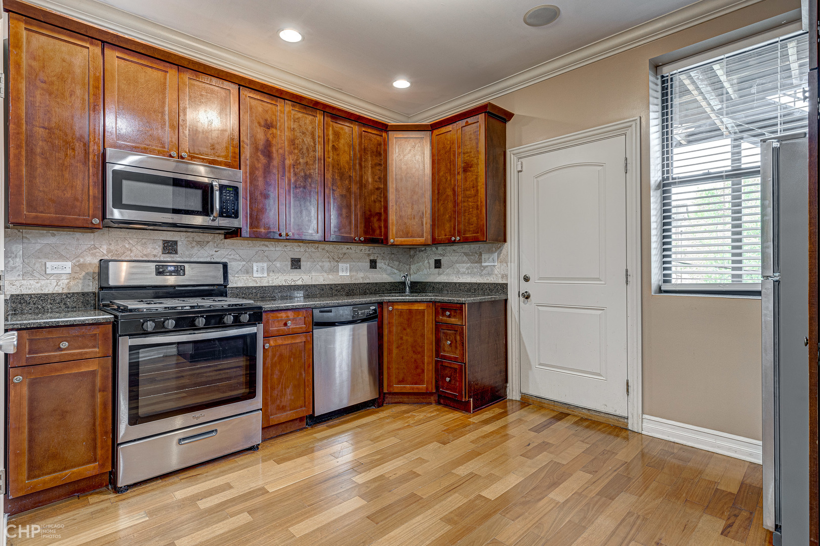 1363 East 64th Street, Unit 2 Chicago, IL 60637 - Photo 11 of 12 a kitchen with stainless steel appliances granite countertop a stove sink microwave and refrigerator
