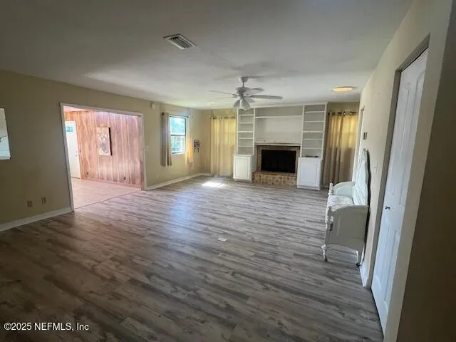 an empty room with wooden floor fireplace and windows