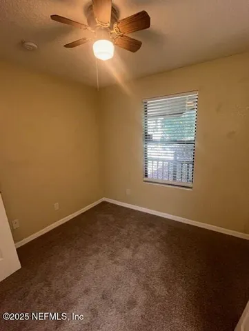 an empty room with a window and a fan