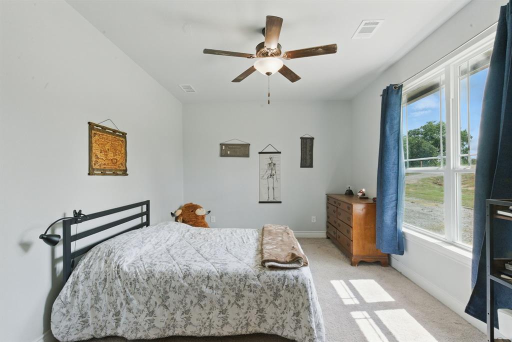 3385 Dps Tower Road Perrin, TX 76486 - Photo 25 of 35 a bedroom with a bed and a chandelier