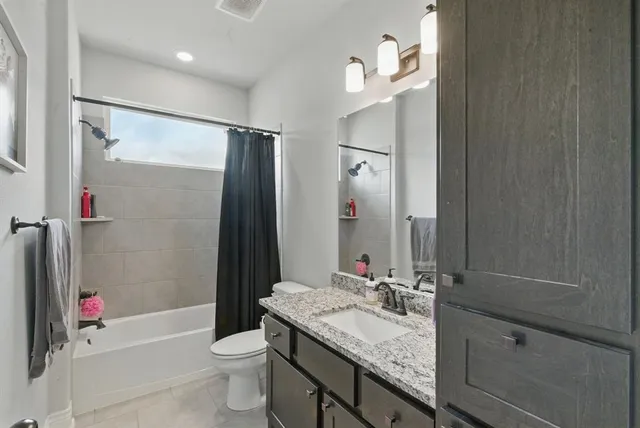 a bathroom with a granite countertop sink a toilet a mirror and shower