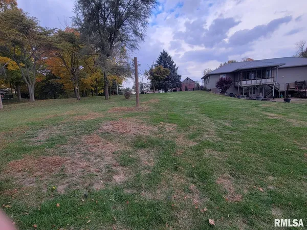 a view of a house with a big yard and large trees
