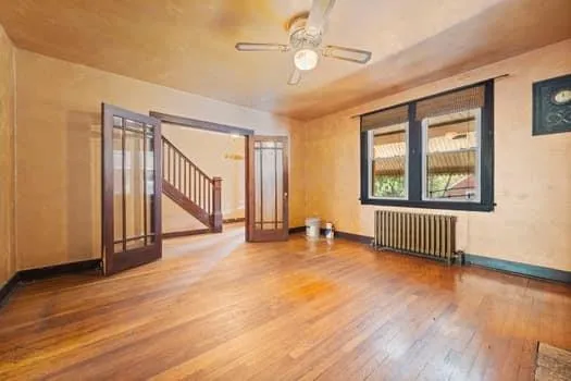a view of an empty room with glass door and wooden floor