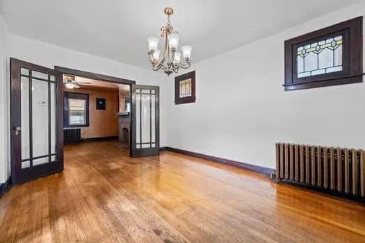 a view of a hallway with wooden floor and a chandelier