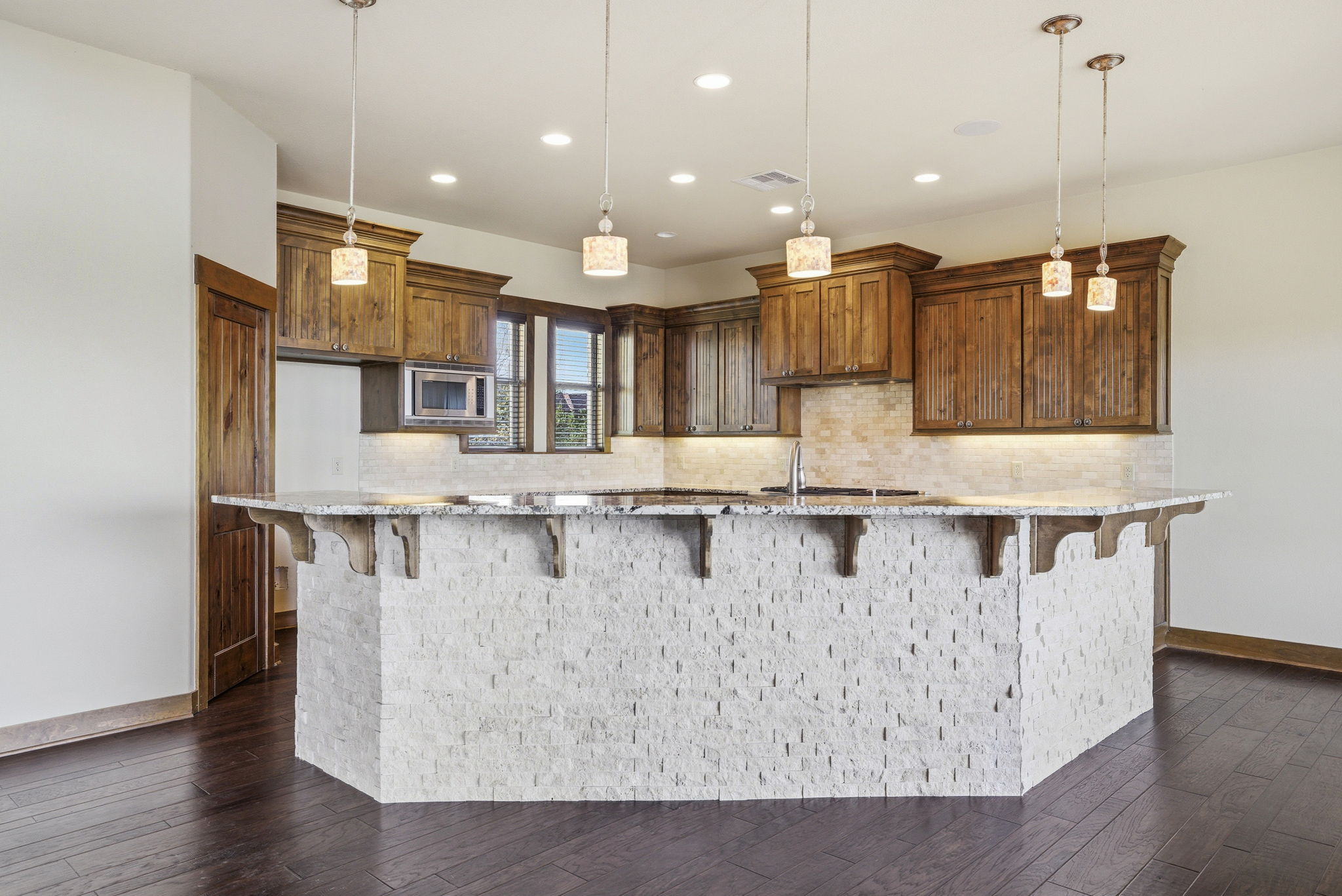 5010 Lookout Ridge Drive Marble Falls, TX 78654 - Photo 14 of 40 Kitchen with wood finish cabinetry, light stone countertops, a kitchen breakfast bar, and dark wood-style floors