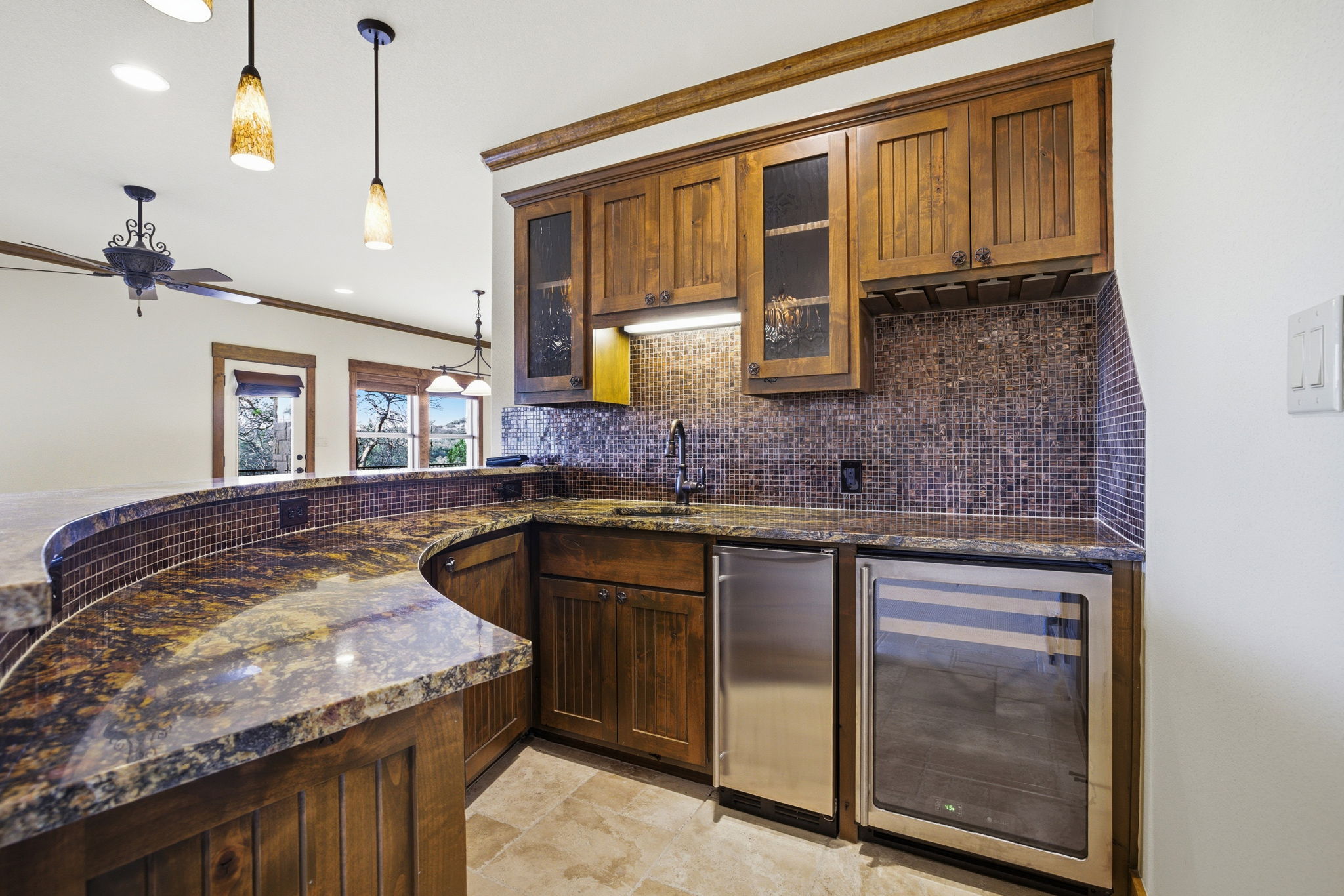 5010 Lookout Ridge Drive Marble Falls, TX 78654 - Photo 23 of 40 Kitchen with wine cooler, dark stone countertops, crown molding, pendant lighting, and glass insert cabinets
