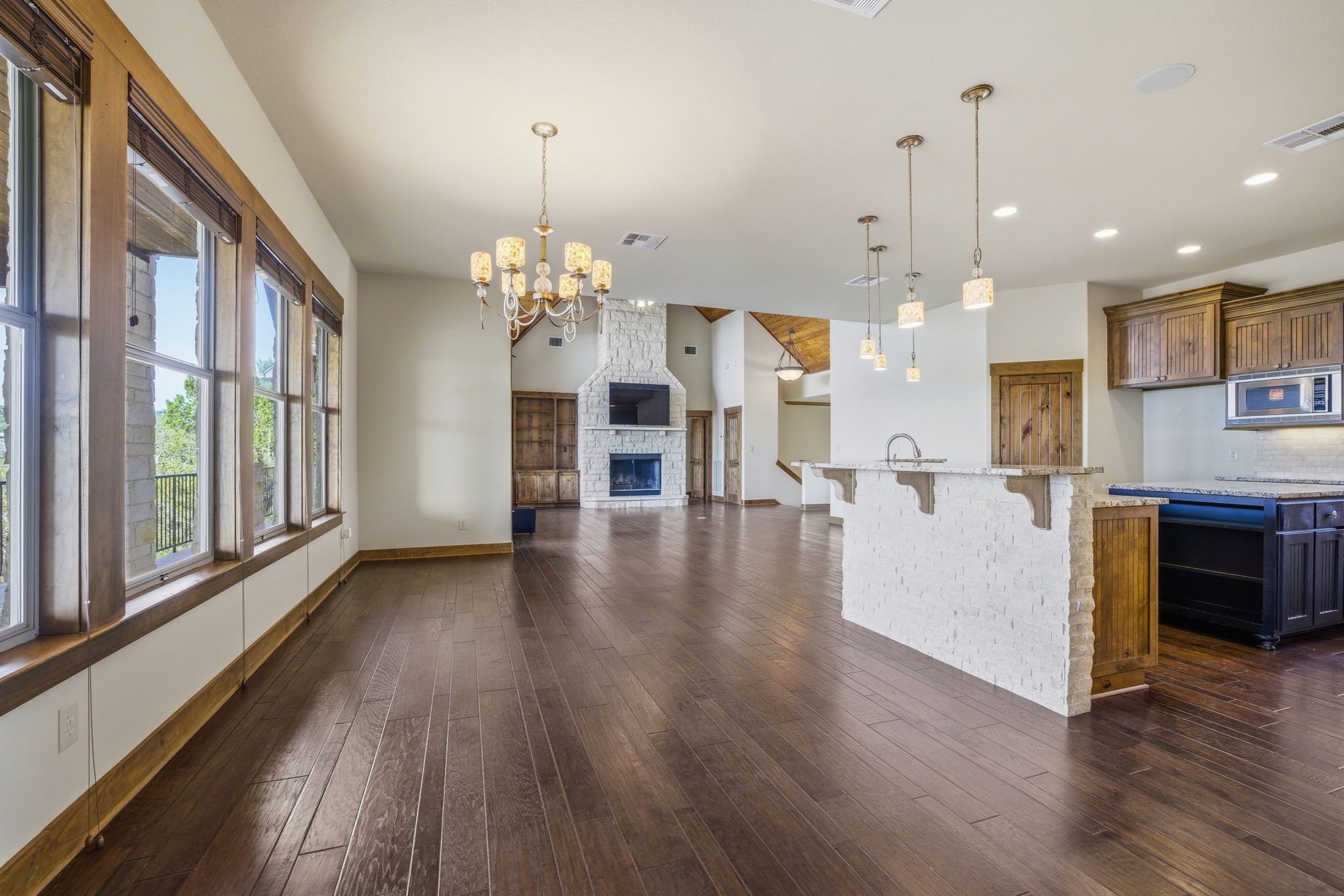 5010 Lookout Ridge Drive Marble Falls, TX 78654 - Photo 39 of 40 Kitchen featuring a center island with sink, open floor plan, light stone countertops, dark wood-style floors, and suspended lighting