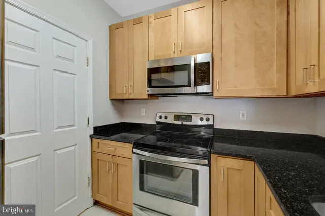 a kitchen with stainless steel appliances granite countertop white cabinets and a stove top oven