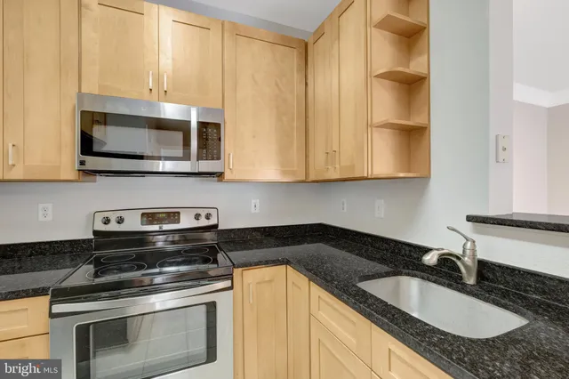 a kitchen with granite countertop a sink stove and microwave