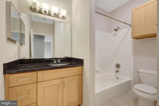 a bathroom with a granite countertop sink a toilet mirror and bathtub