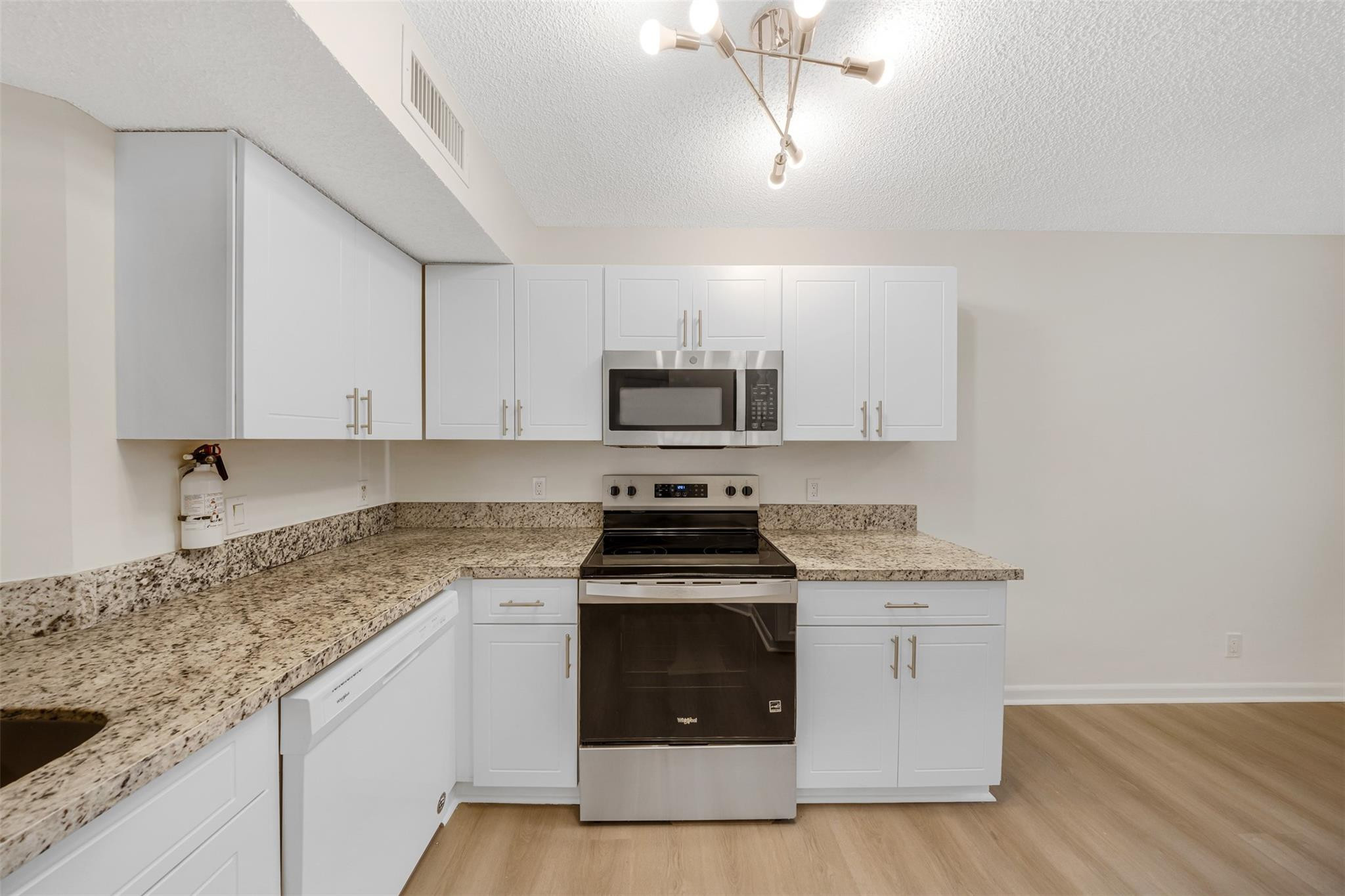 8977 Wiles Road, Unit 102 Coral Springs, FL 33067 - Photo 2 of 37 a kitchen with granite countertop white cabinets stainless steel appliances and a sink