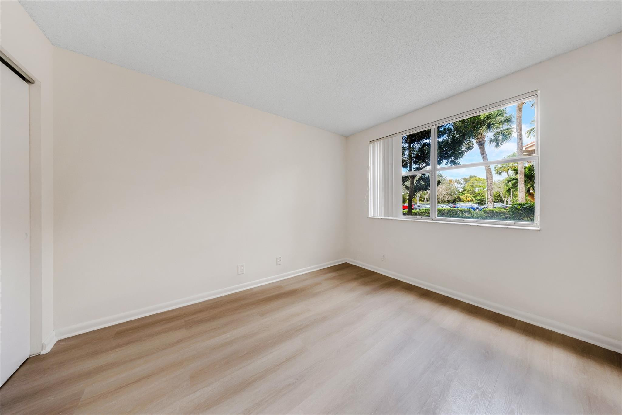 8977 Wiles Road, Unit 102 Coral Springs, FL 33067 - Photo 24 of 37 a view of an empty room with a window and wooden floor