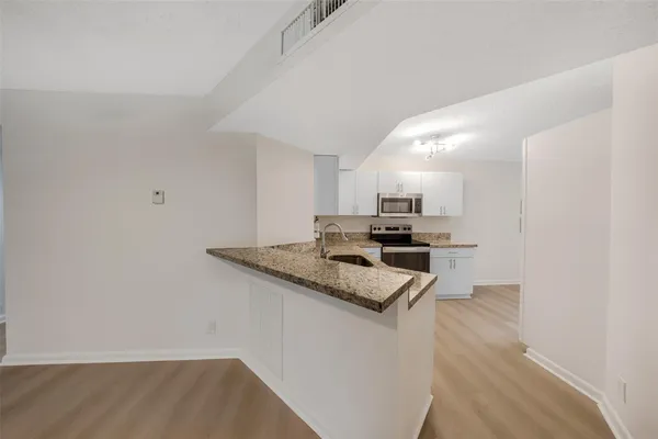 a kitchen with a sink cabinets and wooden floor