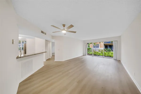 a view of an empty room with window and wooden floor