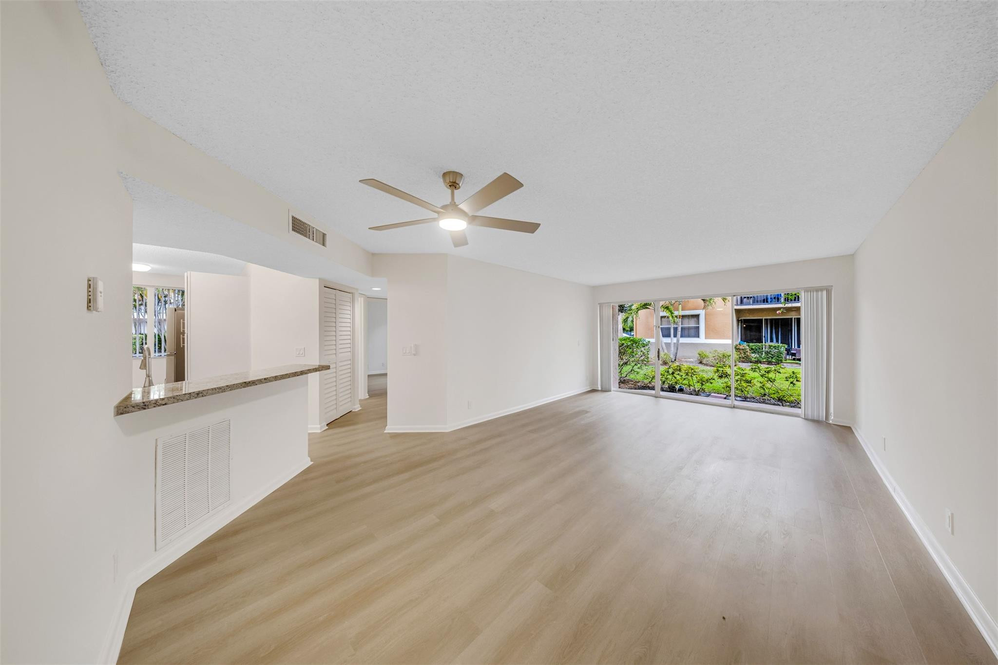 8977 Wiles Road, Unit 102 Coral Springs, FL 33067 - Photo 5 of 37 a view of an empty room with window and wooden floor