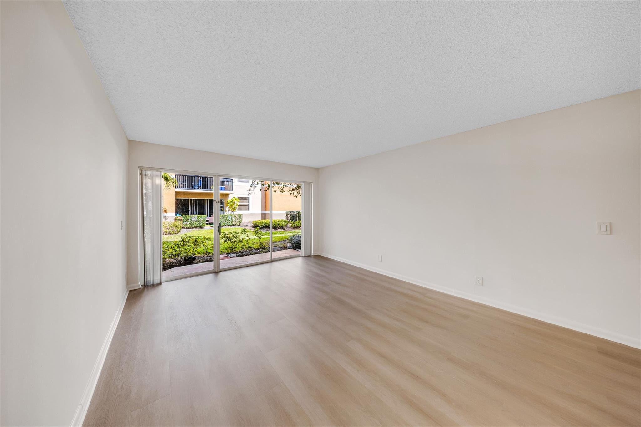 8977 Wiles Road, Unit 102 Coral Springs, FL 33067 - Photo 9 of 37 an empty room with wooden floor and windows