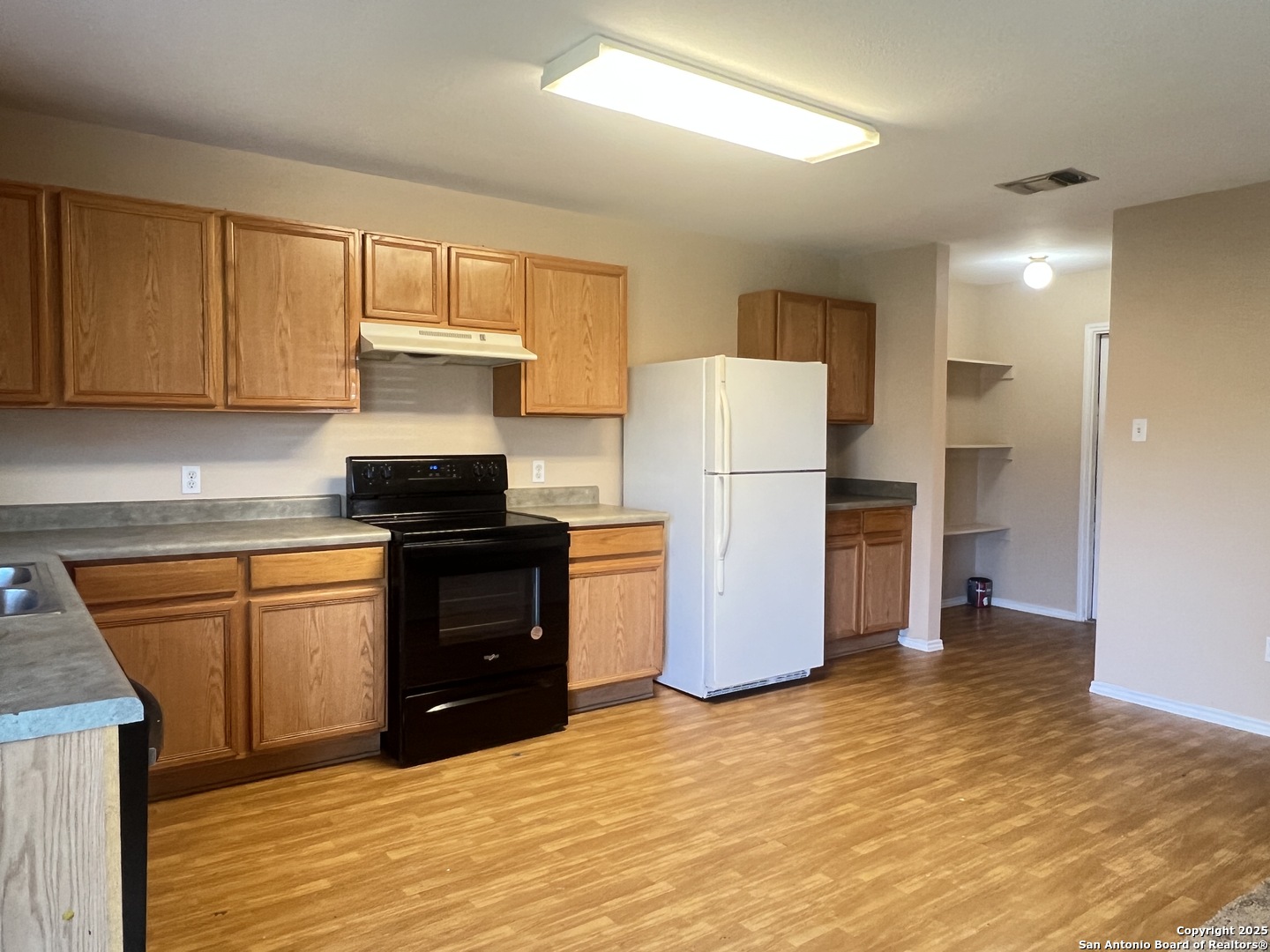 8163 Heights Valley Converse, TX 78109 - Photo 4 of 13 a kitchen with a refrigerator a stove top oven and cabinets