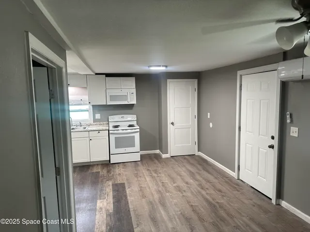 a kitchen with white cabinets and wooden floor