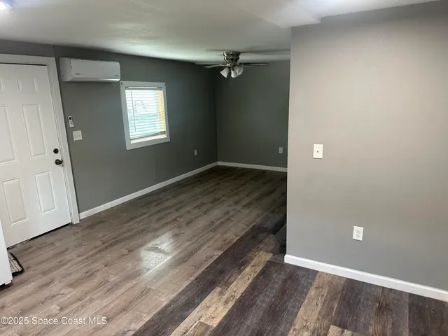 an empty room with wooden floor closet and windows