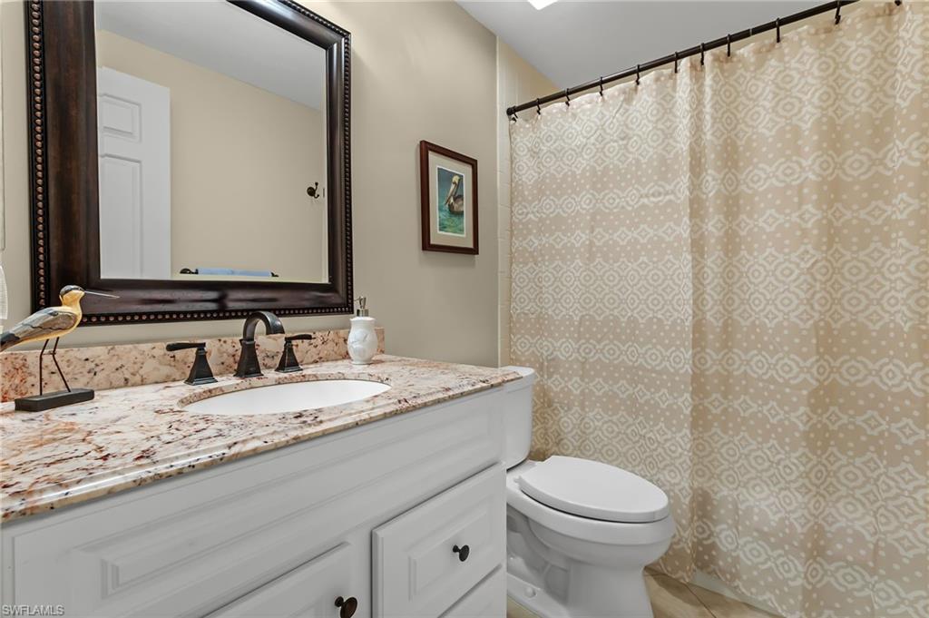 5899 Chanteclair Drive, Unit 214 Naples, FL 34108 - Photo 13 of 24 a bathroom with a granite countertop sink a toilet and a mirror